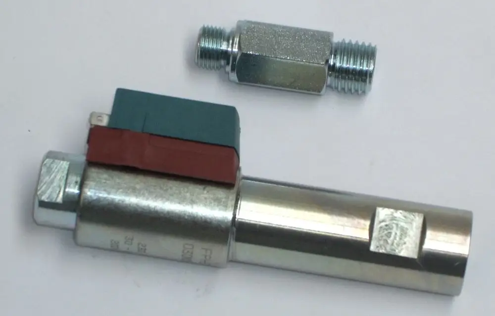 Daikin Ölvorwärmer mit einer zylindrischen Form und zwei Anschlüssen, einer mit einer Farbcodierung aus grünem und rotem Material, auf einem neutralen Hintergrund.